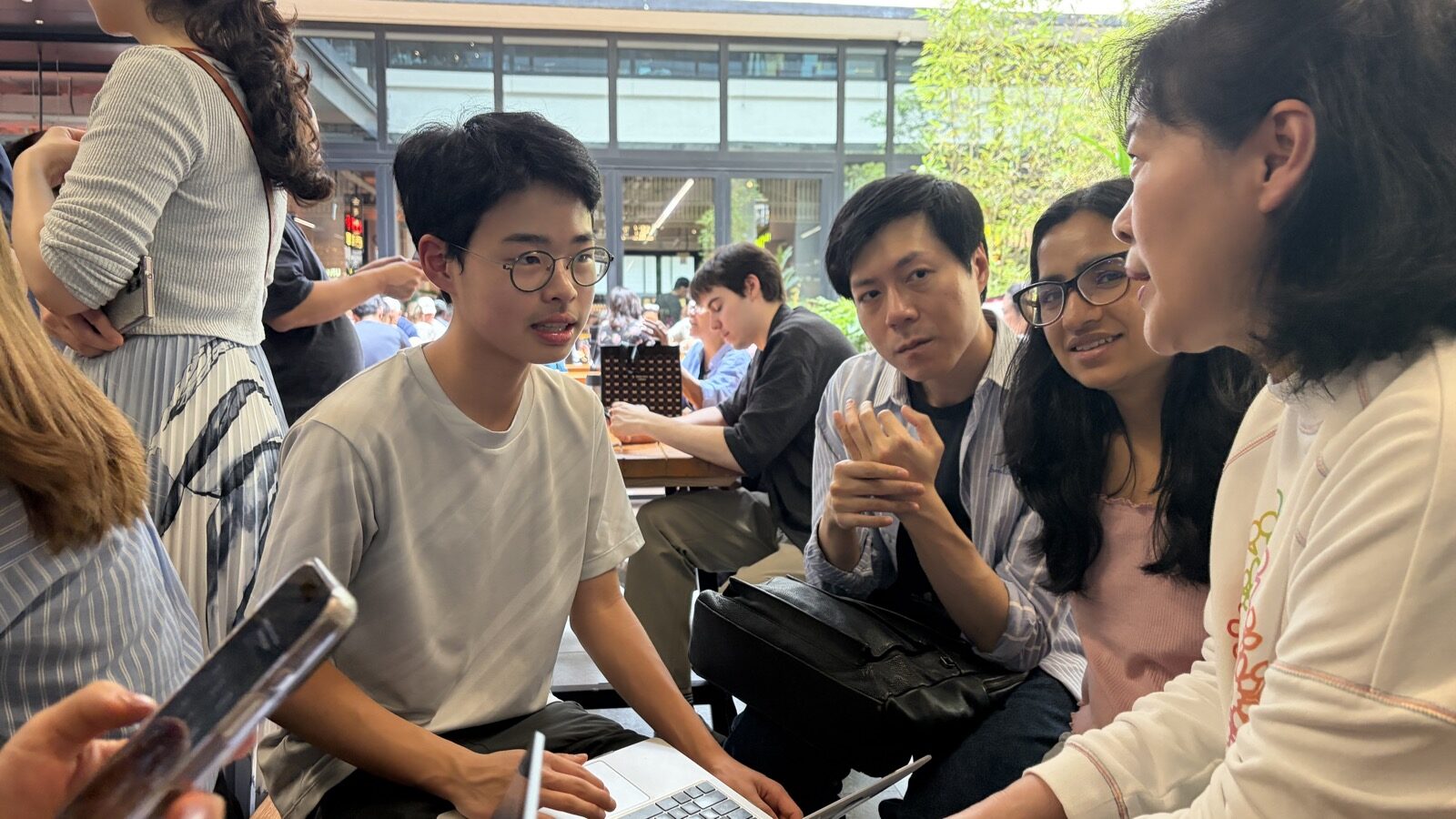 Small group discussing Claude Code around a laptop at Central Market