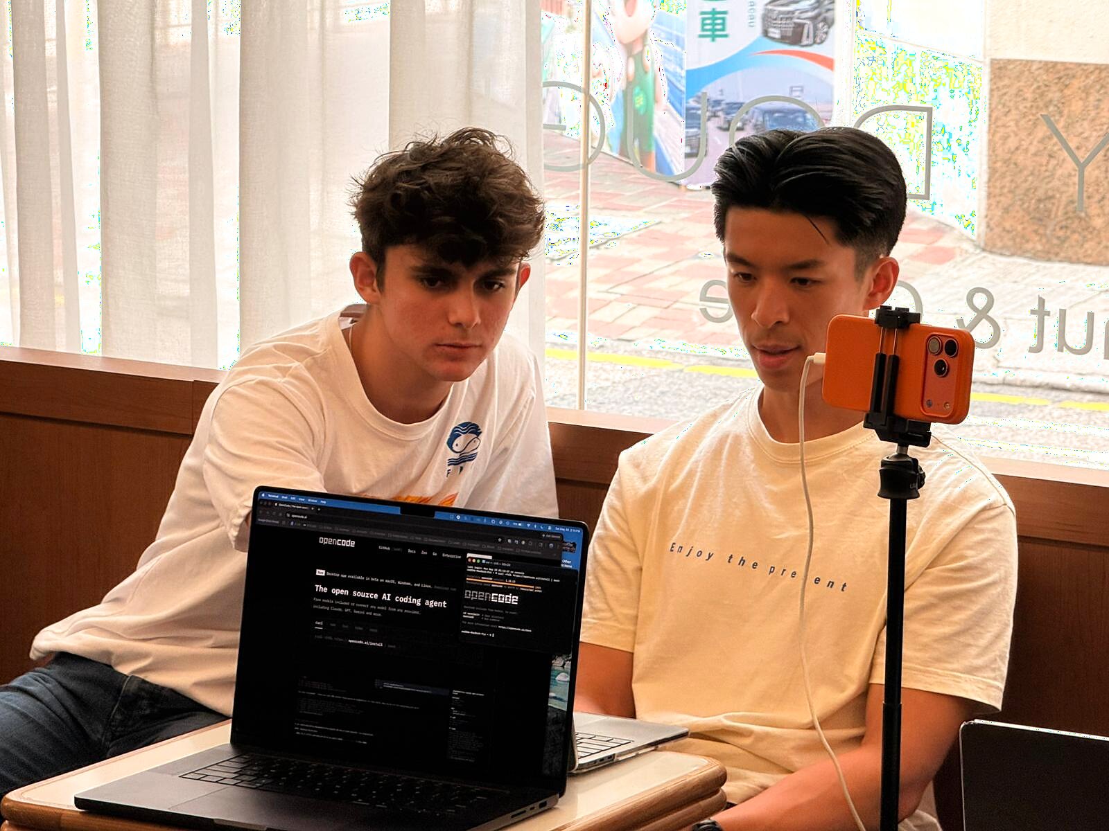 Two builders showing OpenCode on a laptop during the session